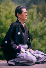 A man sitting on the ground wearing a black robe.